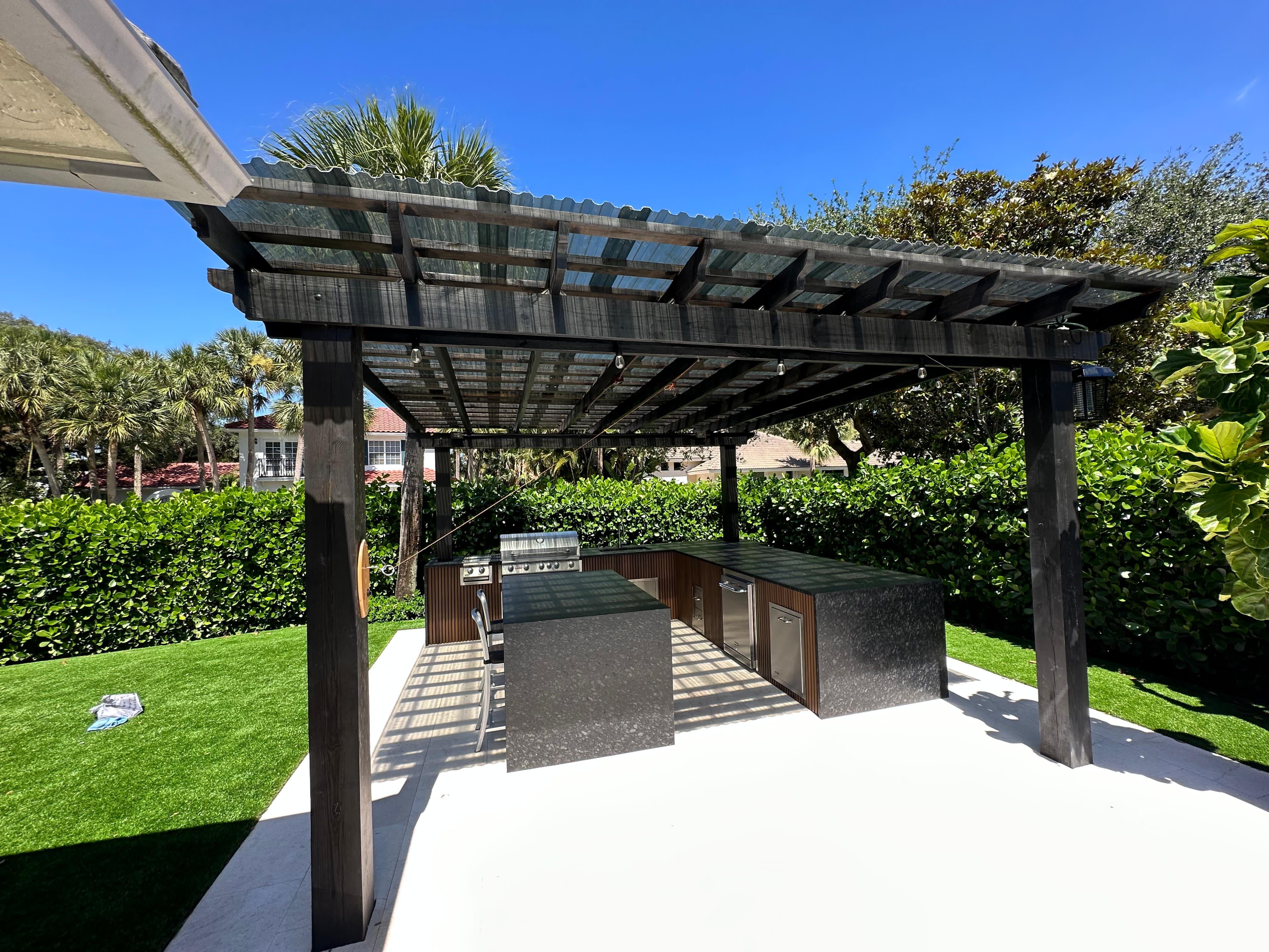 Modern outdoor kitchen with granite countertops, stainless grill under pergola