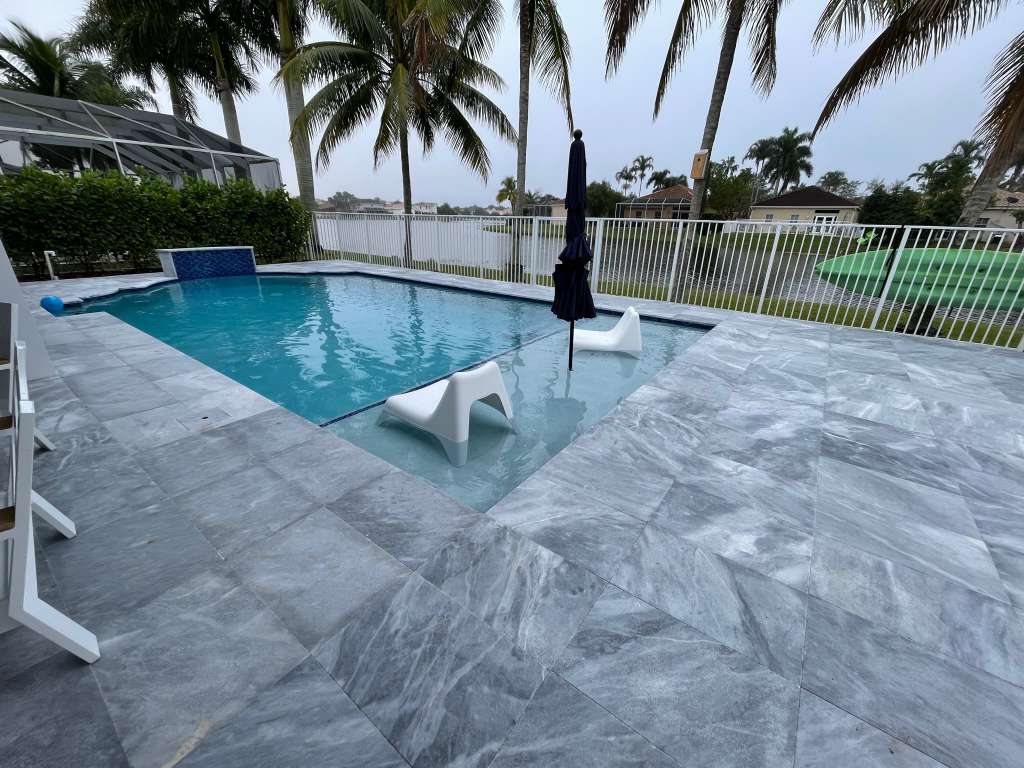 Pool with spa featuring marble-look decking and tile accents