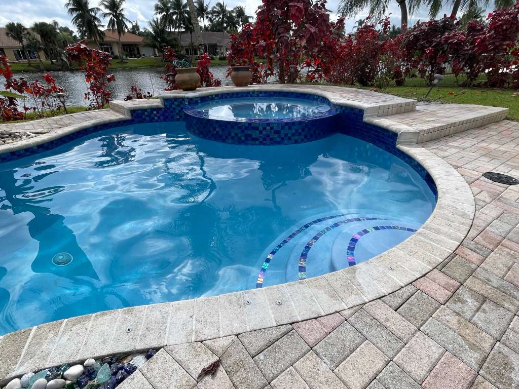 Waterfront pool with tile accents and paver deck